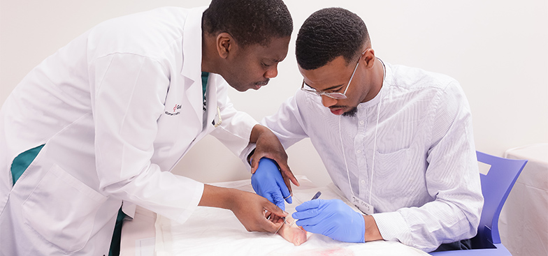 two male students wearing whitecoats practice surgery